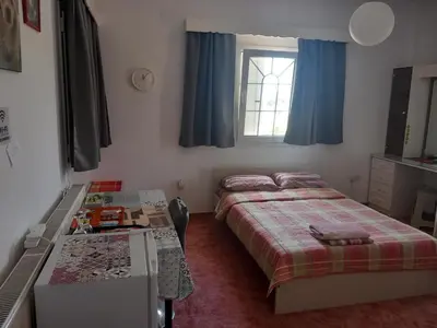 a bedroom with two beds and a desk and a window at Vasilis family room in Mor Menekshe