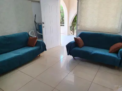 a living room with two blue couches and an open door at The Little House in Voroklini