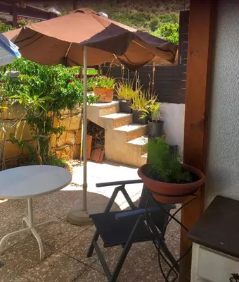 a patio with a table and an umbrella and potted plants at Kuća za odmor Kipar in Pissouri