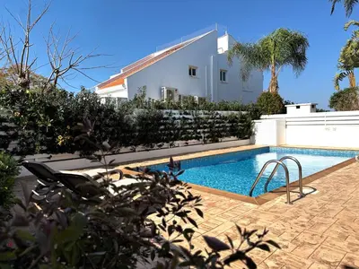 a swimming pool in front of a house at Hephaestus Family Villa, Ayia Triada Beach in Paralimni