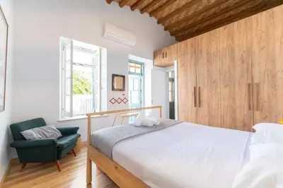 a bedroom with a large bed and a green chair at 1927 Heritage House - Indoor Garden , Old City in Nicosia