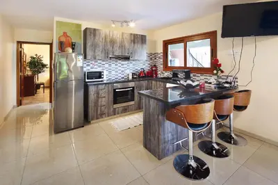 a kitchen with a refrigerator and a counter with bar stools at Olive Tree Apartments in Limassol