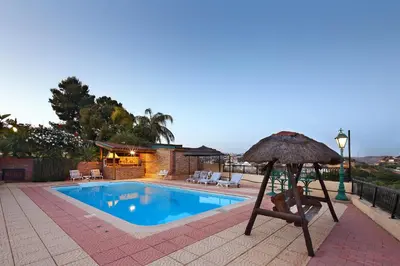 a pool with a chair and an umbrella next to it at Olive Tree Apartments in Limassol