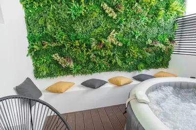 a green wall with pillows next to a hot tub at Kition Urban Suite 2 in Larnaka