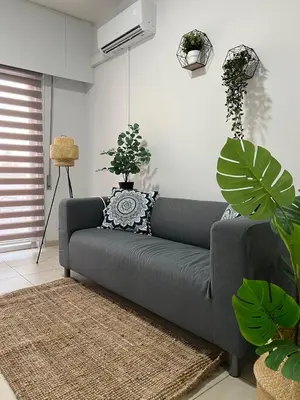 a gray couch in a living room with plants at Tower Court rooms in Larnaka