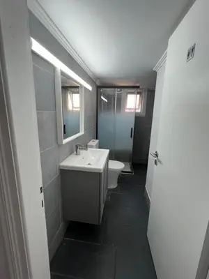 a bathroom with a sink and a toilet and a mirror at Tower Court rooms in Larnaka