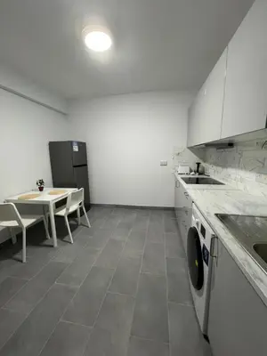 a kitchen with a table and a sink and a dishwasher at Tower Court rooms in Larnaka