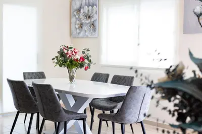 a white dining room table with chairs and a vase of flowers at Villa Alexander The Great in Protaras