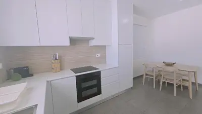 a kitchen with white cabinets and a table with chairs at STAY Space View Apartment in Nicosia