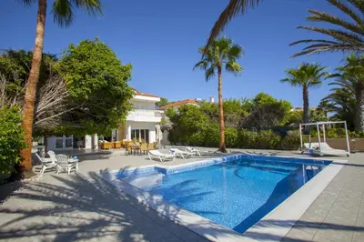 a swimming pool with palm trees and a house at Luxury Villa With Special Sea Views in Meneou
