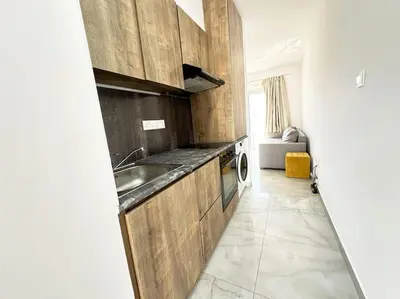 a kitchen with wooden cabinets and a sink at Alice Studio Holiday Apartment - Ayia Napa in Ayia Napa