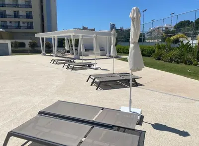 a group of picnic tables and a white umbrella at The Address -Beachfront 2 Bedroom Residence in Limassol