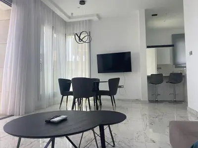 a living room with a table and chairs and a tv at The Address -Beachfront 2 Bedroom Residence in Limassol