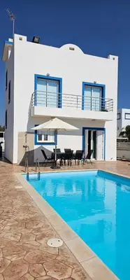 a villa with a swimming pool in front of a house at Villa Amaryllis in Paralimni