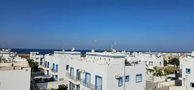 a group of white buildings with the ocean in the background at Villa Amaryllis in Paralimni