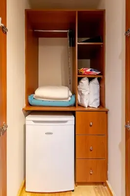 a closet with a white refrigerator and a wooden cabinet at Charming studio with reading nook & city view in Nicosia