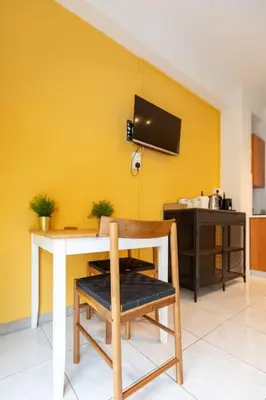 a table and a chair in a room with a yellow wall at Charming studio with reading nook & city view in Nicosia