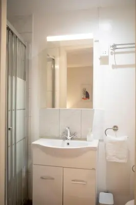 a white bathroom with a sink and a mirror at Spacious studio located in the pedestrian zone in Nicosia