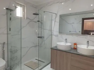 a bathroom with two sinks and a glass shower at Luxury one bedroom - seafront in Limassol