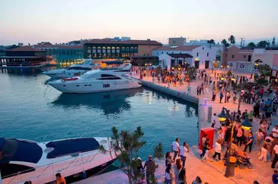 a group of people walking along a dock with boats at Luxury one bedroom - seafront in Limassol