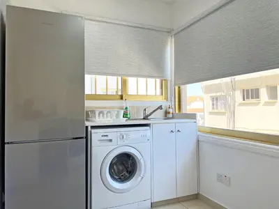 a kitchen with a washing machine and a window at Albert's Apartment Center 21 in Larnaka