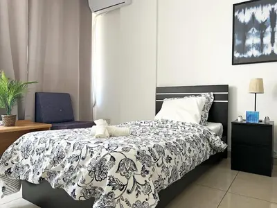 a bedroom with a black and white bed and a chair at Albert's Apartment Center 21 in Larnaka