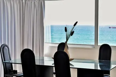 a dining room with a glass table and black chairs at Stunning Top-Floor Beachfront Apartment in Larnaka
