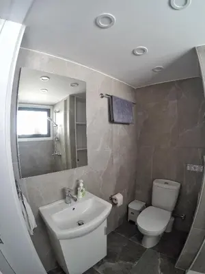 a bathroom with a sink and a toilet and a mirror at Stunning Top-Floor Beachfront Apartment in Larnaka