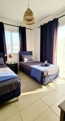 a bedroom with two beds and a chandelier at Crystal aptmnt next to the beach in Protaras