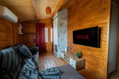 a living room with a couch and a tv on a wooden wall at Ktima To Alliotiko - Lofou 2 in Lofou