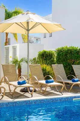 two chairs and an umbrella next to a swimming pool at Villa Elite Blu by Ezoria Villas in Ayia Napa