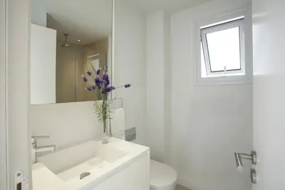 a white bathroom with a sink and a vase of purple flowers at Goodness Villa offers Magnificent Coastal Views in Protaras