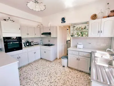a white kitchen with white cabinets and a sink at Grandma's House in Liopetri