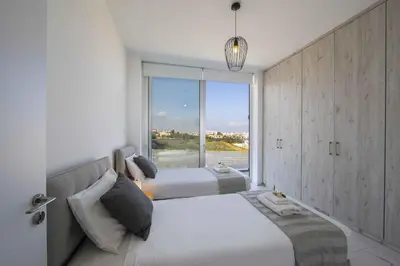 a bedroom with two beds and a large window at Brand New Luxurious Villa With Pool in Protaras
