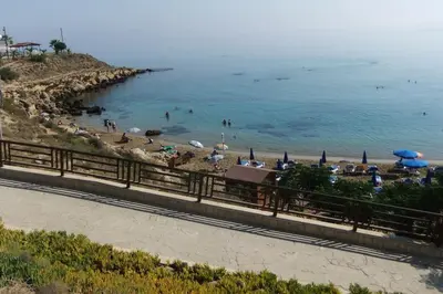 a beach with umbrellas and people in the water at Olivia One Bedroom Apt renovated 2026 in Paralimni