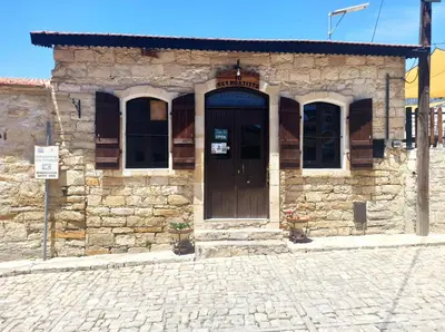 a stone building with a wooden door on a street at Cottage in Anogyra in Anoyira