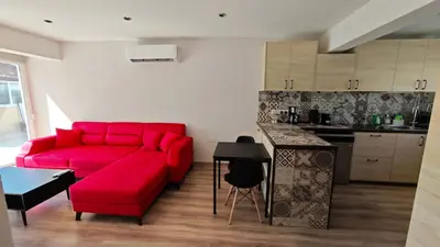 a living room with a red couch and a kitchen at Modern 1-bedroom home in Larnaca with a private garden ideal for long stays and remote work in Larnaka