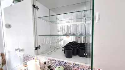 a glass cabinet with mugs on it in a kitchen at Boho Greek Haven with Orange Grove Views Near Beach in Larnaka