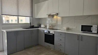a white kitchen with white cabinets and a microwave at STAY Local Apartment in Larnaka