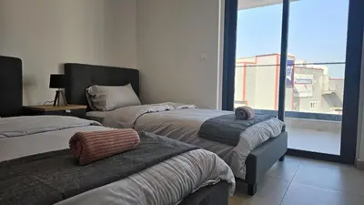 a bedroom with two beds and a large window at STAY Diamond Apartment in Larnaka