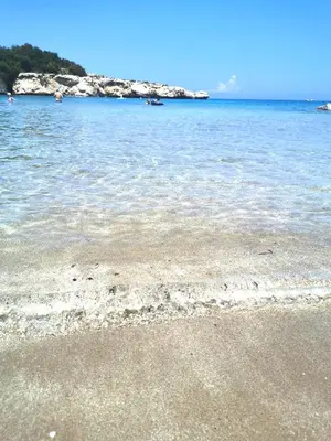 a beach with the ocean and rocks in the background at Holiday apartment in Kyklades Complex with gym&pool in Paralimni