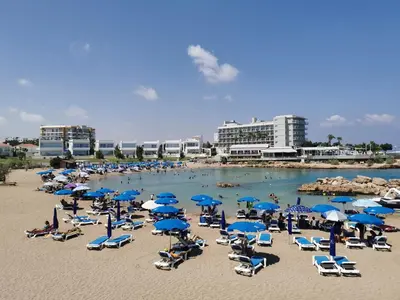 a beach with a bunch of chairs and umbrellas at Relax by the sea in Protaras