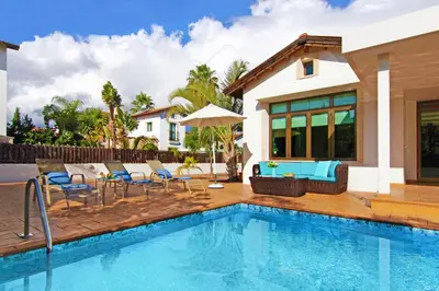 a swimming pool with chairs and a house at Villa Merry in Ayia Napa