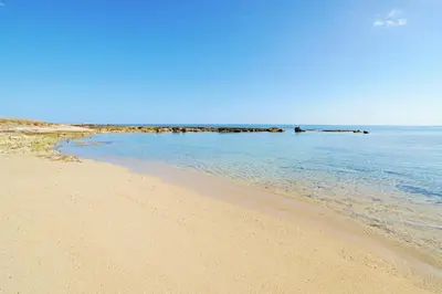 a sandy beach with a group of rocks in the water at Villa Merry in Ayia Napa