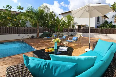 a patio with a couch and an umbrella next to a pool at Villa Merry in Ayia Napa