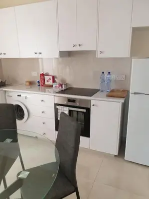 a kitchen with a glass table and white cabinets at Cozy comfortable 2-bedroom apartment in Limassol