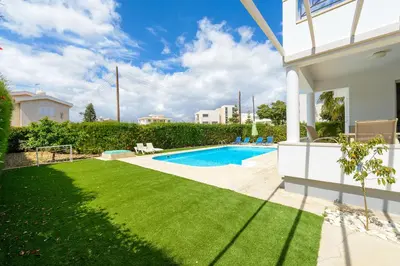 a backyard with a swimming pool and green grass at Merab Center Villas in Ayia Napa