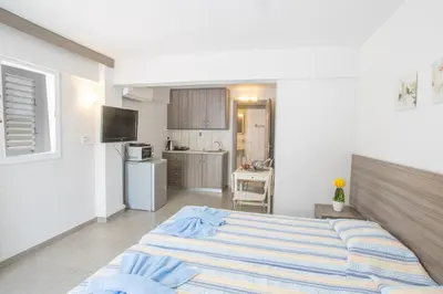 a bedroom with a large bed and a kitchen at Merab Napa Suites in Ayia Napa