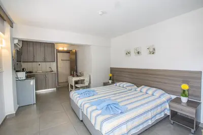 a bedroom with a large bed and a kitchen at Merab Napa Suites in Ayia Napa