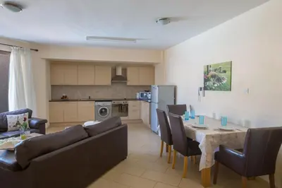 a kitchen and a living room with a table and chairs at Napiana Apartments in Ayia Napa